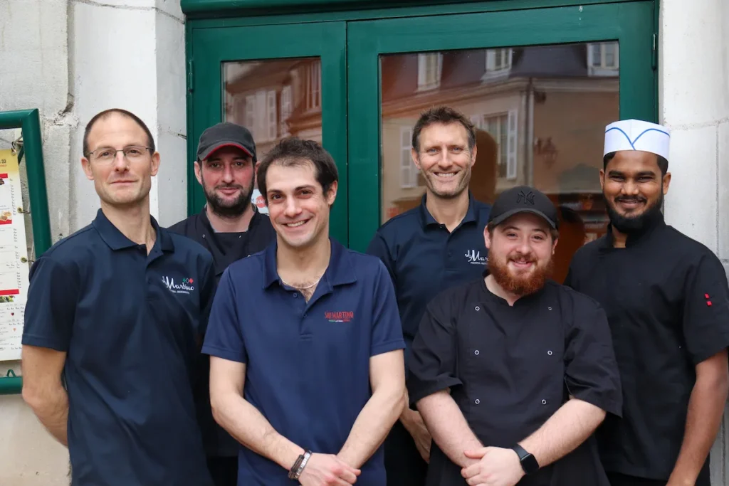 Restaurant staff posing outside entrance in uniforms
